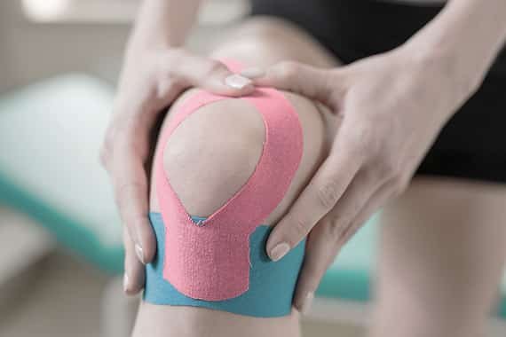 kinesiotaping knee of woman at clinic